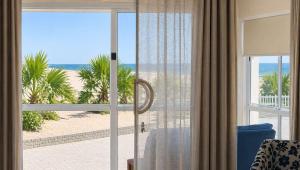 a room with a view of the beach through a sliding glass door at Sunset Sails 2 Apartment in Langstrand