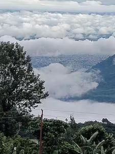 a view of a lake with clouds and trees at Aasara Homestay Bhimtal Orchard Villa in Bhīm Tāl