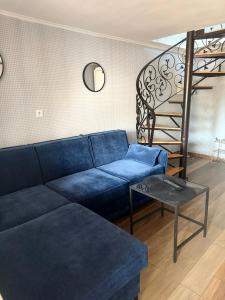 a living room with a blue couch and a spiral staircase at NA SKARPIE in Łomża
