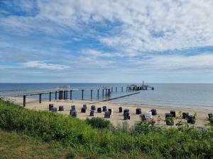 a beach with chairs and a pier and the ocean at Ferienwohnung 15 in Koserow in Koserow