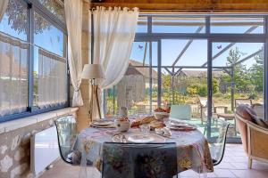 a dining room with a table and a large window at Le Grand Pré du Clos Champêtre in Longué