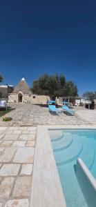 a swimming pool with two blue benches and a house at Casa Relax Isabelle in Alberobello