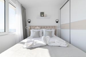 a white bedroom with a large white bed with white pillows at Elegant Seaview 1bd in Dobre Vode in Dobra Voda
