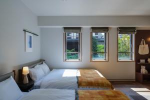 a bedroom with two beds and three windows at The Apartment Hotel Shibuya 3 in Tokyo +24 photos