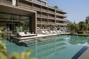 a hotel with a swimming pool in front of a building at Feldhof DolceVita Resort in Naturno