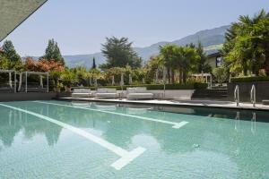 a swimming pool with chairs and trees and mountains at Feldhof DolceVita Resort in Naturno +71 photos
