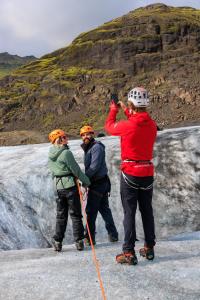 a group of three people standing on top of a glacier at Adventure Stay in Vík