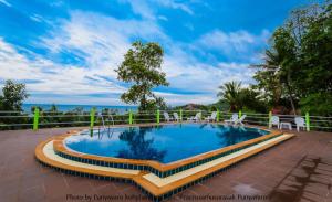 a swimming pool with chairs and the ocean in the background at J.B.Hut Bungalows in Haad Yao