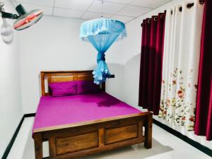 a bedroom with a bed with purple sheets and a blue umbrella at Malwathu oya resort in Anuradhapura