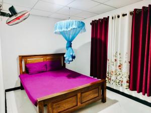 a bedroom with a purple bed with an umbrella at Malwathu oya resort in Anuradhapura