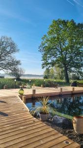 a wooden deck with a pond in a yard at Gîte et chambres d'hôtes Aux Charlots in Lagarde-Hachan