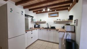 a kitchen with white cabinets and a refrigerator at Gîte et chambres d'hôtes Aux Charlots in Lagarde-Hachan