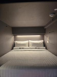 a bed with white sheets and pillows in a room at Straits Heritage Hostel in Singapore