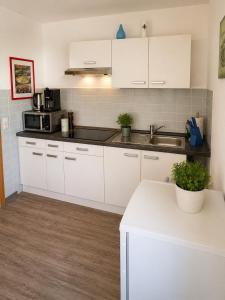 a kitchen with white cabinets and a sink at Apartment Hope Inn in Groß-Zimmern +7 photos