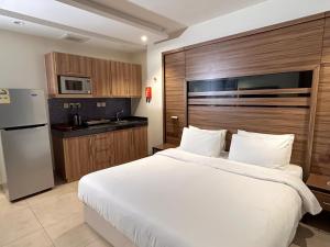 a bedroom with a large white bed and a kitchen at بيت لمار 3 للشقق المخدومه in Riyadh