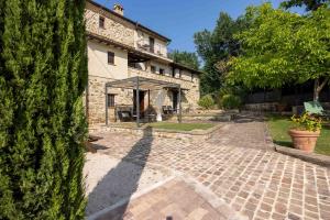 a house with a large tree next to a courtyard at Agriturismo La Palazzetta di Assisi in Assisi