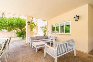 a patio with white chairs and a couch at Villa Arenas in El Arenal