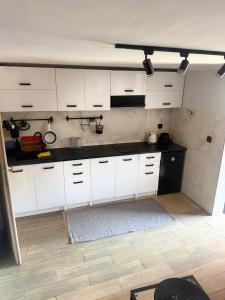 a kitchen with white cabinets and a black counter top at NA SKARPIE in Łomża