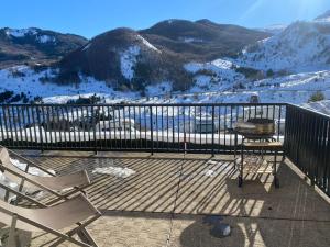 a balcony with two chairs and a table and snow covered mountains at Ibon de Anayet in Formigal +6 photos