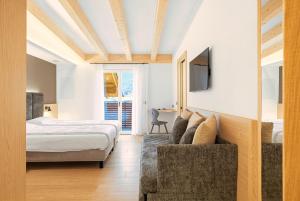 a bedroom with a bed and a couch and a tv at Residence Diamant in Andalo