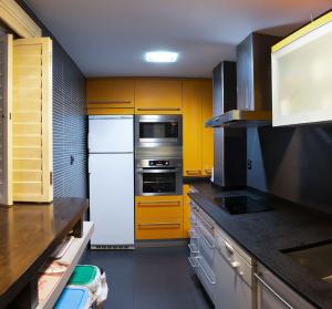 a kitchen with yellow cabinets and a white refrigerator at Ibon de Anayet in Formigal