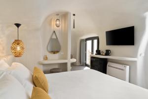ein Schlafzimmer mit einem weißen Bett und einem Fernseher in der Unterkunft Aeon Suites - Adults Only by Mr and Mrs White in Pirgos