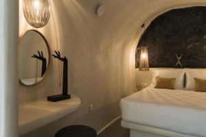 ein Schlafzimmer mit Bett, Spiegel und Waschbecken in der Unterkunft Aeon Suites - Adults Only by Mr and Mrs White in Pirgos + 121 Fotos