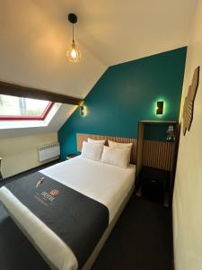 a bed in a room with a green wall at Hôtel les Paturelles in Avesnelles