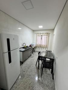 a kitchen with a refrigerator and a table in it at Casa nova e confortavel, Itabirito, MG in Itabirito