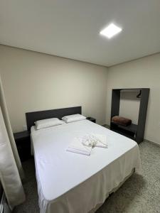 a bedroom with a large white bed with towels on it at Casa nova e confortavel, Itabirito, MG in Itabirito