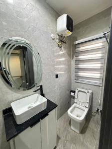 a bathroom with a sink and a toilet and a mirror at Skybuilt Apartment in Abuja +14 photos