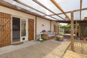 a patio with a wooden pergola and a couch at La Cabane du Bassin in Lanton