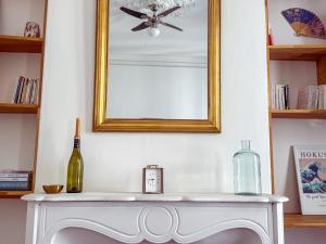 a mirror above a white table with a bottle of wine at Superbe appartement spacieux, calme, central in Toulon +38 photos