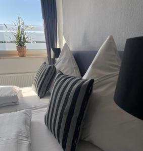 a bed with three pillows on it with a window at Hotel KAUP in Paderborn