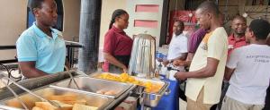 a group of people standing around a buffet with food at KH KH Hotel in Kasese