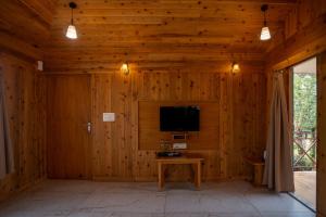 a living room with a tv and a wooden wall at Resort Bihanga in Chālsa Mahābāri