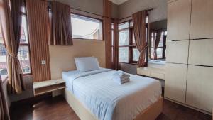 a small bedroom with a bed and two windows at Umahnis Villa in Ngabean