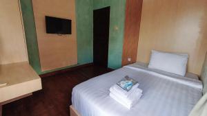 a bedroom with a white bed with a towel on it at Umahnis Villa in Ngabean