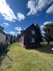 a wooden house on a field with a fence at Mountain Cabin Retreat - Terrace, BBQ, Hot Tub in Lunca Bradului