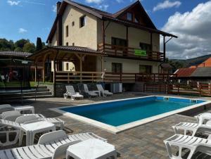 a swimming pool with chairs and a house at Casa Bujor de Munte Dragoslavele in Dragoslavele
