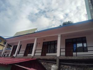 a white building with a blue roof and windows at Royal Orbit By StayApart in Sonprayag