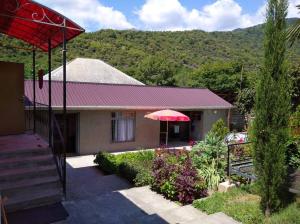 a house with a red umbrella in front of it at Zaqatala-Car riverside cottage in Zaqatala