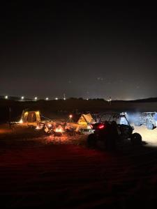 a group of tents and vehicles in a field at night at Desert Safari in Margham +3 photos