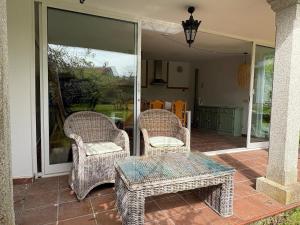 two wicker chairs and a table on a patio at The Eira - Spacious duplex with lush garden in Nigrán