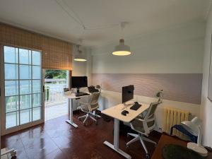 an office with two desks and two monitors and chairs at The Eira - Spacious duplex with lush garden in Nigrán