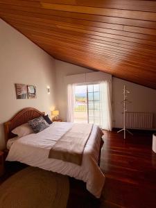 a bedroom with a large bed with a wooden ceiling at The Eira - Spacious duplex with lush garden in Nigrán
