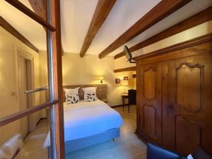 a bedroom with a bed and a wooden cabinet at Hôtel de l'Ange in Niedermorschwihr