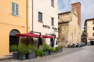 a hotel with red umbrellas in front of a building at Hotel Verdi Pisa in Pisa