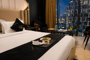 a hotel room with a bed with a plate of food on it at Aquila Grand Suites - Noida Sector 136 in Noida