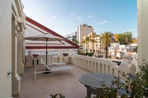 a balcony with a bench and an umbrella at CISNES PALACE in Sanlúcar de Barrameda
